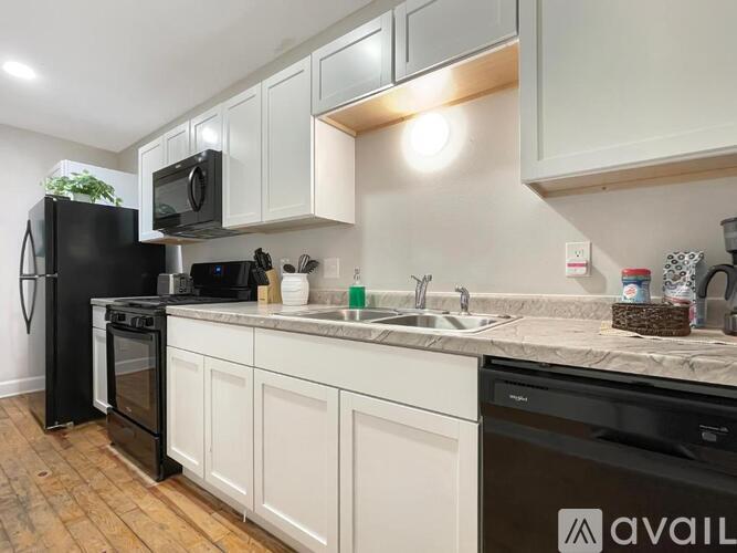 A kitchen with a black fridge and white cabinets.