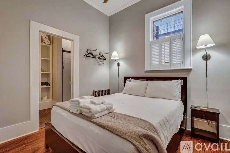 A bedroom with a large bed and a window with white shutters.