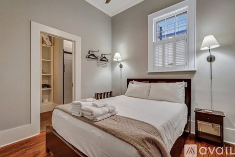 A bedroom with a large bed and a window with white shutters.