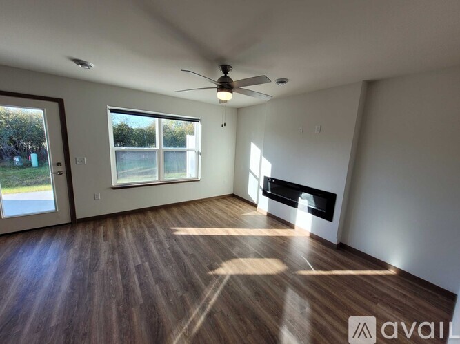 A spacious room with a rug, a ceiling fan, and two doors.