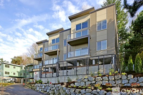 A modern apartment building with a stone wall in front.
