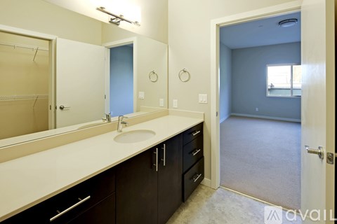 A bathroom with a sink, mirror, and a door leading to another room.