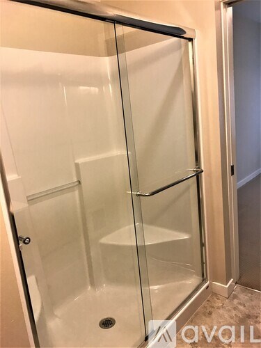 A glass shower stall with a drain in the floor.