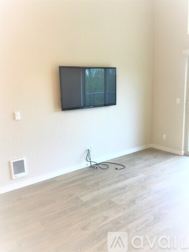 A room with a flat screen TV mounted on the wall and a cable running across the floor.