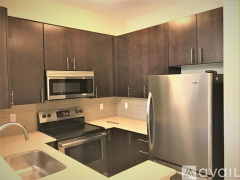 A kitchen with a stainless steel refrigerator, microwave, and oven.
