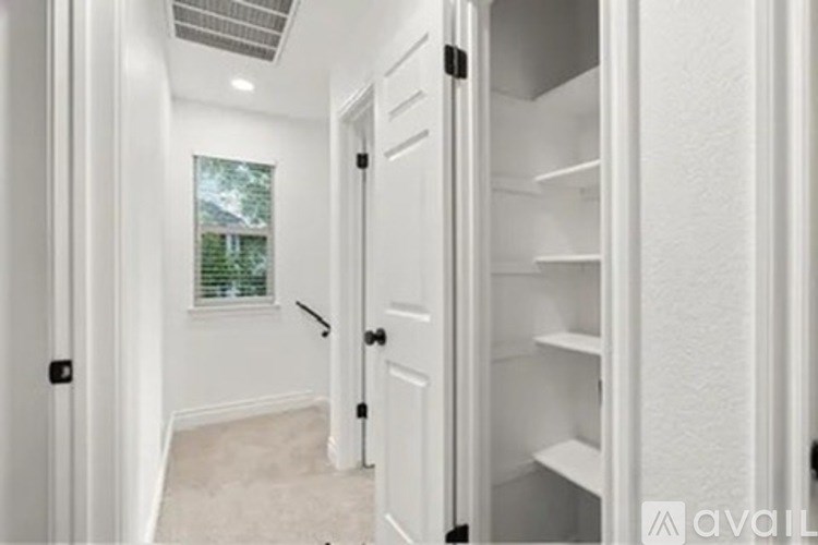 A white pantry with a door open to a hallway.
