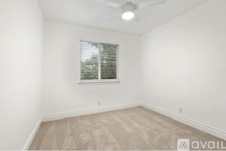 A room with a window and a fan on the ceiling.