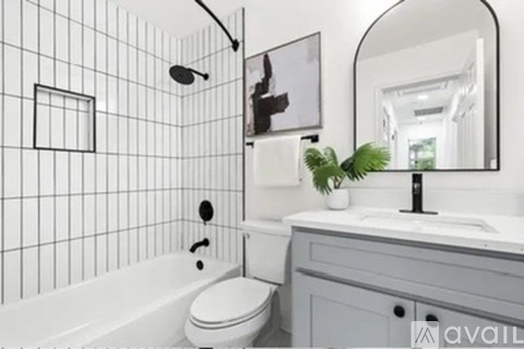 A bathroom with a white tiled wall and a white bathtub.