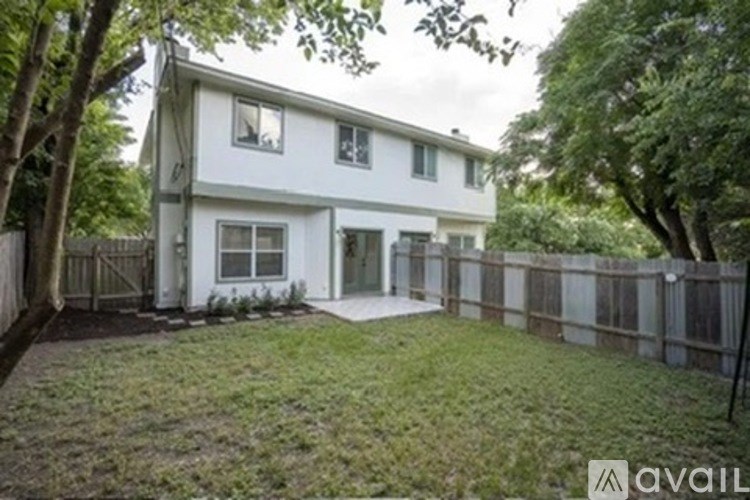 A white two-story house with a fenced yard.