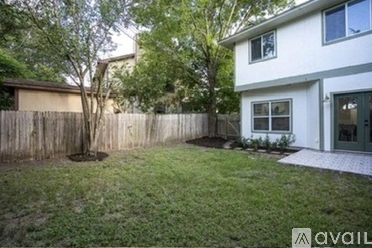 A house with a fence and a tree in front of it.