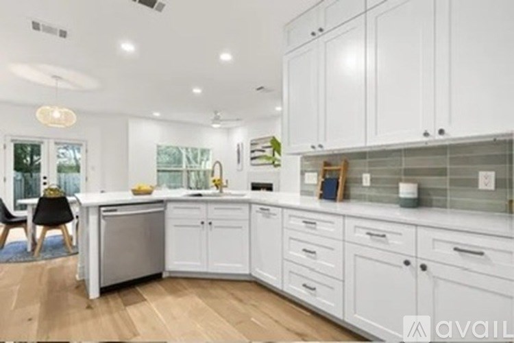 A modern kitchen with white cabinets and a wooden floor.