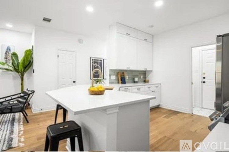 A modern kitchen with a white countertop and a dining area with a black chair.