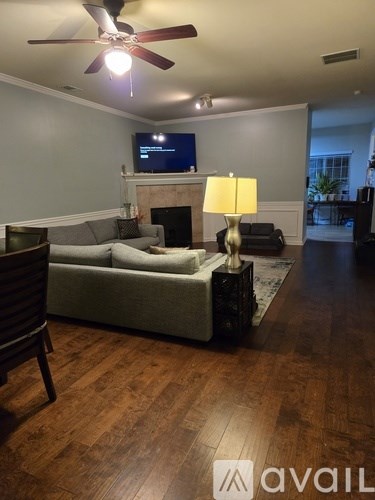 A living room with a grey couch and a television on the wall.