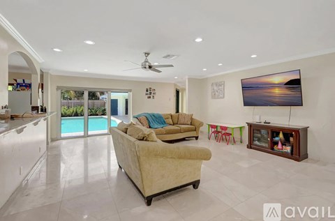 A living room with a beige couch and a television on the wall.