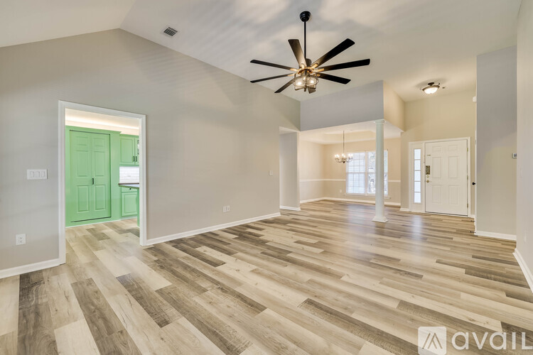 A spacious room with wooden flooring and a ceiling fan.