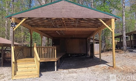 A wooden pavilion with a green roof and a sign that reads "EXIT" is surrounded by trees.