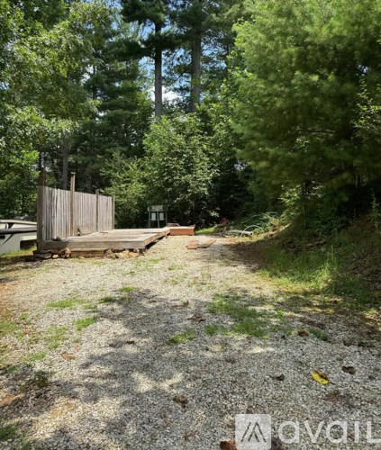 A gravel path leads to a wooden gate in a wooded area.