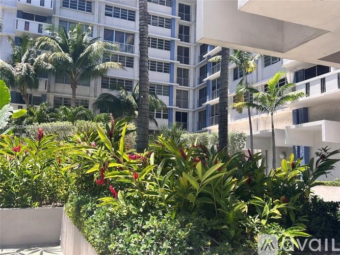 A lush green garden in front of a white building with balconies.