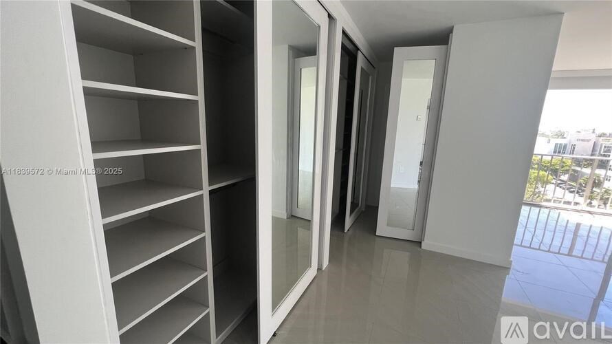 A white shelving unit with glass doors is in a room with a view of a balcony.