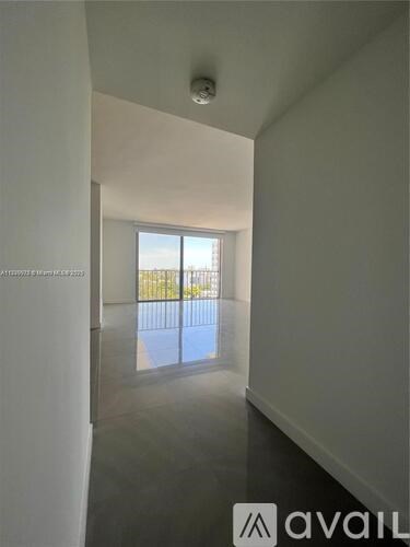 A room with a view of a fence and trees through a window.