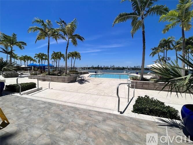 A pool surrounded by palm trees and a clear blue sky.