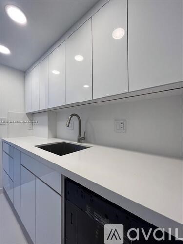 A modern kitchen with white cabinets and a black dishwasher.