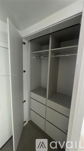 A white closet with shelves and drawers is open.