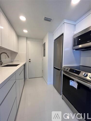 A modern kitchen with white cabinets and stainless steel appliances.