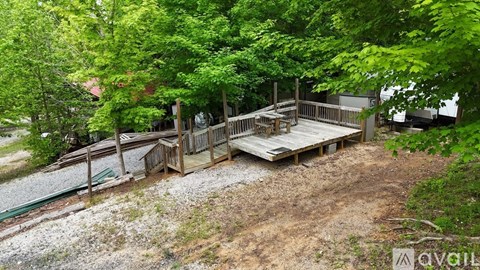 A wooden deck surrounded by trees and gravel.