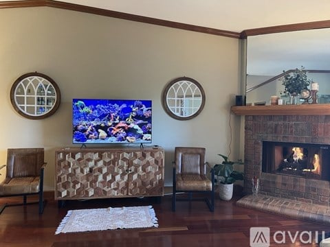 A living room with a fireplace and a television on the wall.