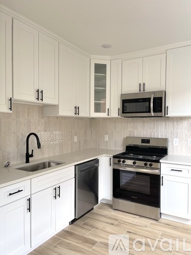 A kitchen with white cabinets and a black microwave.