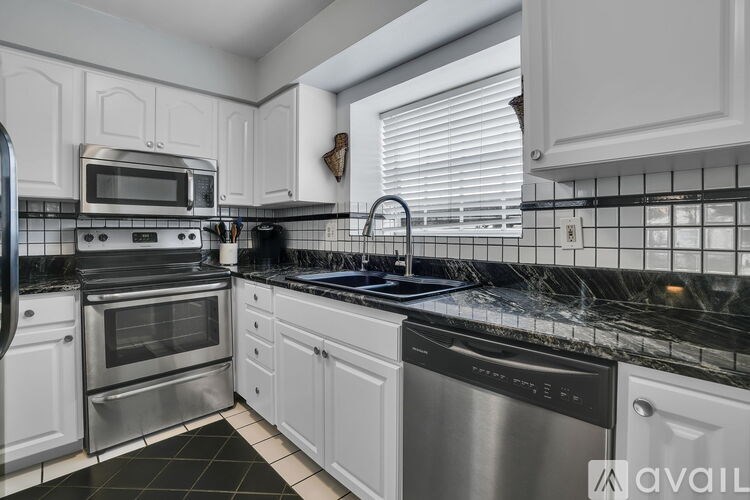 A kitchen with white cabinets and black countertops.