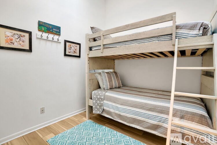 A room with a bunk bed and a blue rug on the floor.
