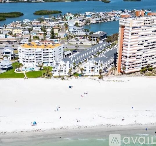 A beachfront view with people on the beach and buildings in the background.