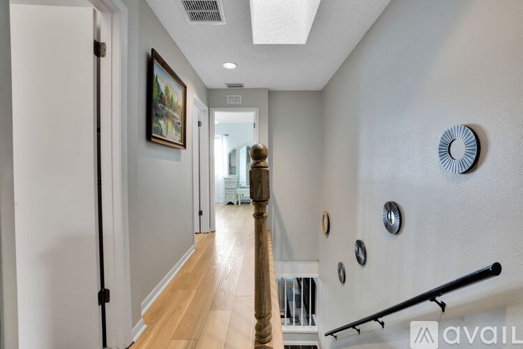 A hallway with a person walking in the distance and a painting on the wall.