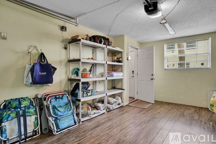 A room with a white door, a window with blinds, and a shelf with bags and shoes.