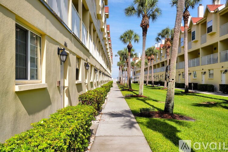 A row of apartment buildings with a sidewalk and palm trees.