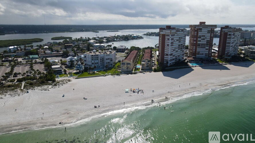 A beach scene with people on the sand and buildings in the background.