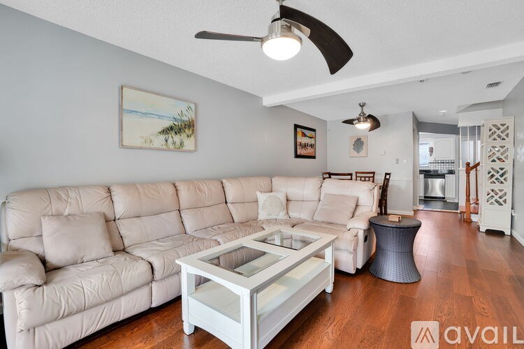 A living room with a white couch and a glass coffee table.