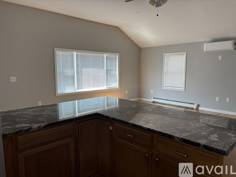 A kitchen with a marble countertop and wooden cabinets.