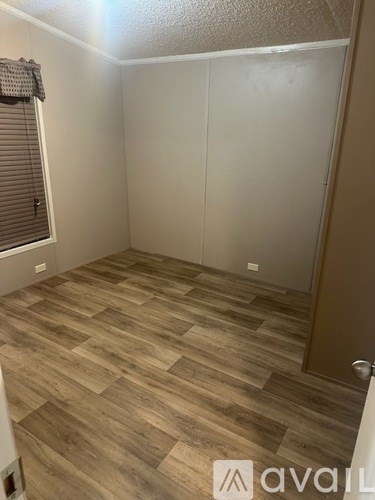 A room with wooden flooring and a door on the right side.