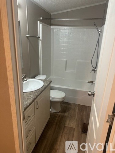 A small bathroom with a toilet, sink, and shower.
