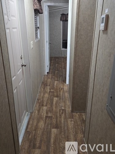 A hallway with wood flooring and white walls.