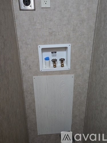 A white box with a blue label and two gold-colored objects inside is mounted on a wall.