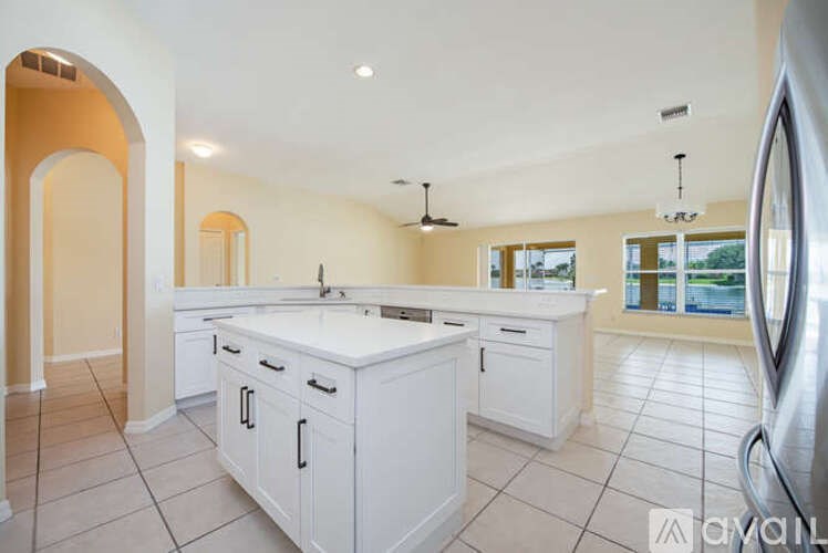 A kitchen with white cabinets and a large island.