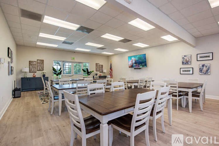 A room with a long table and chairs, a television, and a painting on the wall.