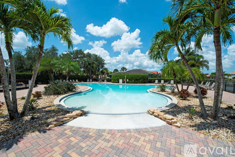 A pool surrounded by palm trees and a brick border.