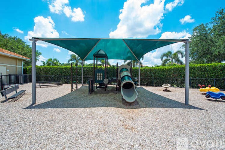 A playground with a green canopy and a slide.