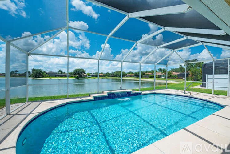 A swimming pool under a white canopy with a view of a lake and trees.