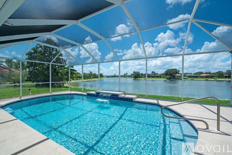 A swimming pool under a white canopy with a view of a lake and trees.